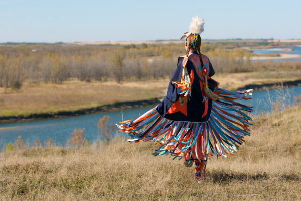 first nation dancer First Nation dancer in traditional attire near a river