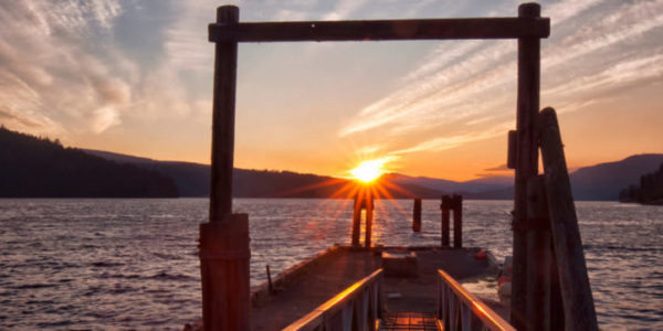 A dock leading to water with a setting sun