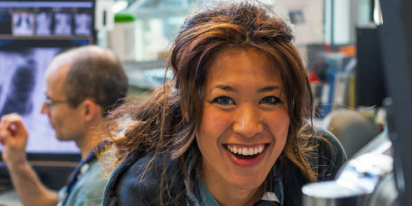 A smiling nursing student in a busy office