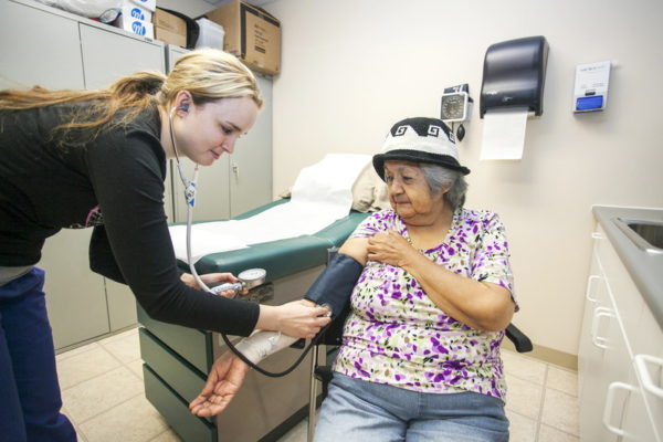A senior woman getting her blood pressure tested by a nursing student