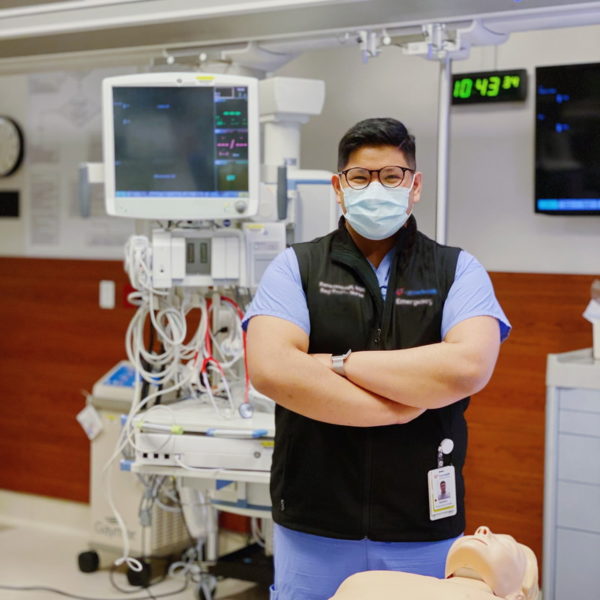 International nursing student standing proudly in front of a training dummy
