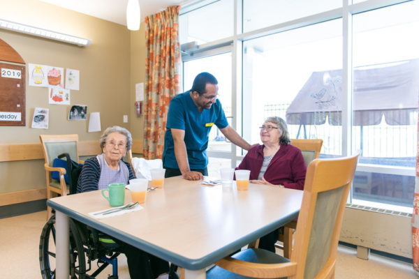 International nursing student smiling and chatting with two elderly women