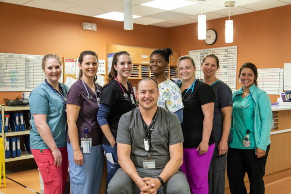Group of 8 international nursing students huddled together and smiling for the camera